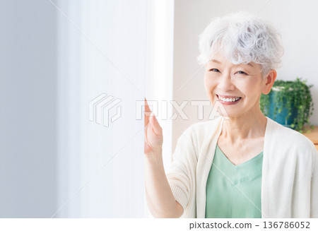Senior woman looking out the window 136786052