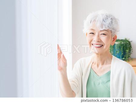 Senior woman looking out the window 136786053