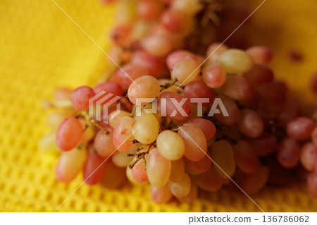 Fresh and vibrant grapes ready to delight on a sunny yellow surface 136786062