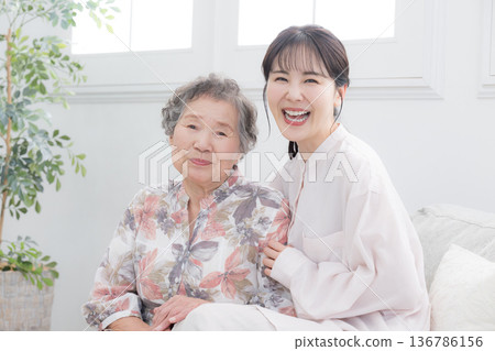 Close-up of smiling grandchild and elderly grandmother, looking at camera for caregiving or parent-child image Close-up of smiling grandchild and elderly grandmother, looking at camera for caregiving or parent-child image 136786156