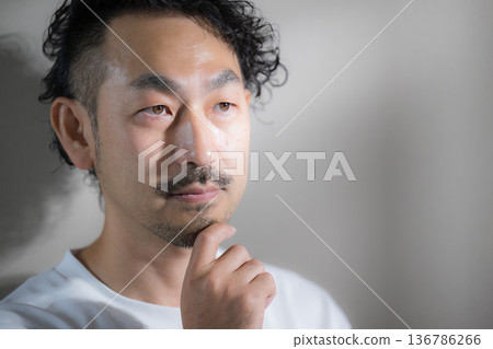 一位英俊的中年男子留著鬍鬚，鏡頭特寫他正在脫毛和護理鬍鬚，他撫摸著下巴，神情憂慮地思考著。 136786266