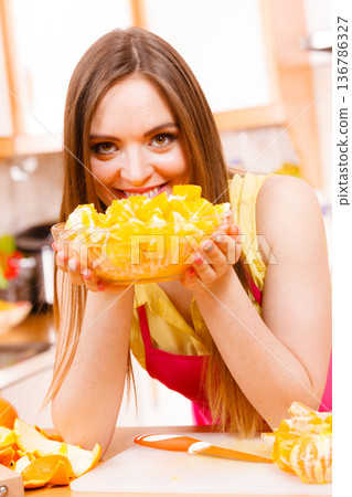 Woman holds bowl full of sliced orange fruits 136786327
