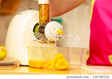 Making orange juice in juicer machine in kitchen Making orange juice in juicer machine in kitchen 136786328