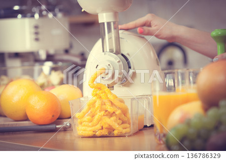 Woman making orange juice in juicer machine Woman making orange juice in juicer machine 136786329