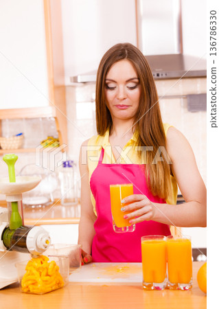 Woman in kitchen drinking fresh orange juice 136786330