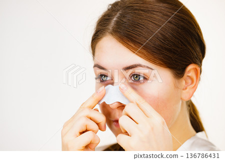 Woman applying pore strips on nose Woman applying pore strips on nose 136786431