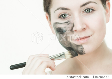 Woman being apply black carbo mask to face Woman being apply black carbo mask to face 136786448