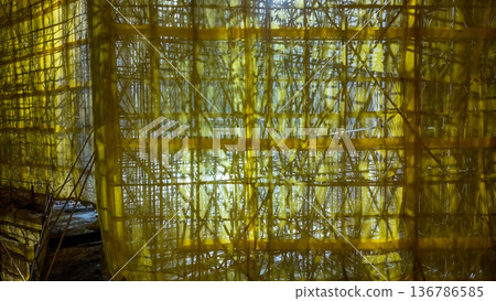 Yellow mesh construction scaffolding illuminated during evening Feb 5 2026 Yellow mesh construction scaffolding illuminated during evening Feb 5 2026 136786585