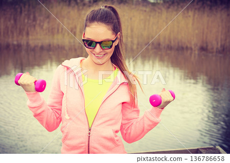 Woman exercising with dumbbells outdoor Woman exercising with dumbbells outdoor 136786658