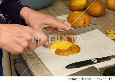 Cutting Potato Wedges on a Plastic Cutting Board Cutting Potato Wedges on a Plastic Cutting Board 136786916