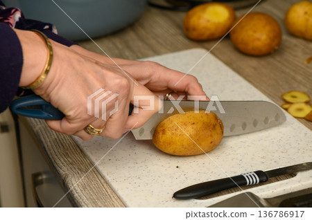 Slicing Potatoes for Roasting on a Kitchen Board Slicing Potatoes for Roasting on a Kitchen Board 136786917