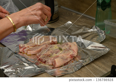 Pressing Fresh Rosemary onto Pork Chops Before Cooking 136786928