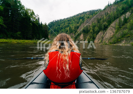 Girl in a life jacket rafting on a packraft on the river Girl in a life jacket rafting on a packraft on the river 136787079