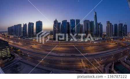 Aerial view of Jumeirah lakes towers skyscrapers night to day timelapse with traffic on sheikh zayed road. Aerial view of Jumeirah lakes towers skyscrapers night to day timelapse with traffic on sheikh zayed road. 136787222