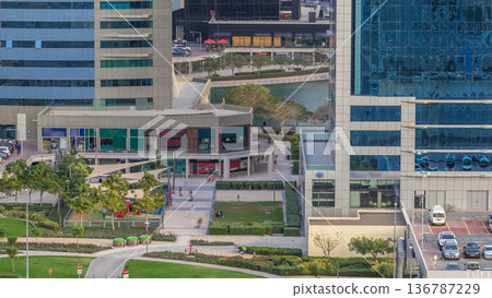 Aerial view of green area near Jumeirah lakes towers skyscrapers timelapse with car parking Aerial view of green area near Jumeirah lakes towers skyscrapers timelapse with car parking 136787229