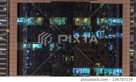 Windows of the multi-storey building of glass and steel lighting inside and moving people within timelapse Windows of the multi-storey building of glass and steel lighting inside and moving people within timelapse 136787239