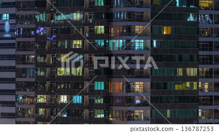 Windows of the multi-storey building of glass and steel lighting inside and moving people within timelapse Windows of the multi-storey building of glass and steel lighting inside and moving people within timelapse 136787253