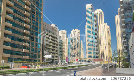 Dubai Marina with Skyscrapers timelapse and traffic on the street near concrete road bridge through the canal Dubai Marina with Skyscrapers timelapse and traffic on the street near concrete road bridge through the canal 136787256