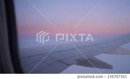 Airplane wing view during sunset with colorful sky and clouds Airplane wing view during sunset with colorful sky and clouds 136787301