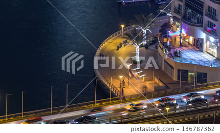 Promenade and canal in Dubai Marina with luxury skyscrapers and yachts around night timelapse, United Arab Emirates 136787362