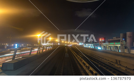 Front cabin POV view from modern driver-less metro train rush forward, along night Dubai, smooth timelapse. Front cabin POV view from modern driver-less metro train rush forward, along night Dubai, smooth timelapse. 136787970