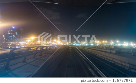 Front cabin POV view from modern driver-less metro train rush forward, along night Dubai, smooth timelapse. 136787971