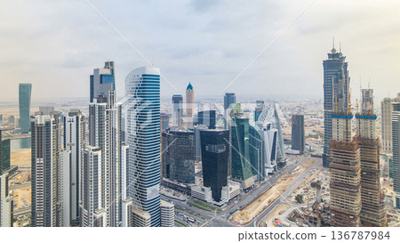 Dubai's business bay towers before sunset timelapse. Rooftop view of some skyscrapers and new towers under construction. 136787984