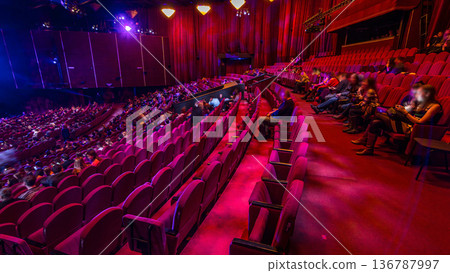 Spectators gather in the auditorium and watch the show in theatre timelapse. Large hall with red armchairs seats Spectators gather in the auditorium and watch the show in theatre timelapse. Large hall with red armchairs seats 136787997