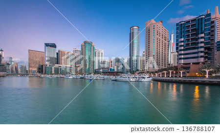 Dubai Marina towers and yachts reflected in water of canal in Dubai day to night timelapse Dubai Marina towers and yachts reflected in water of canal in Dubai day to night timelapse 136788107