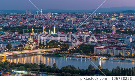 Aerial panoramic view over Vienna city with skyscrapers, historic buildings and a riverside promenade day to night timelapse in Austria. 136788238