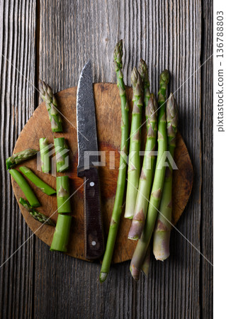 Fresh green asparagus arranged on round wooden cutting board Fresh green asparagus arranged on round wooden cutting board 136788803