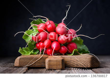Fresh red radishes with leafy tops on wooden board Fresh red radishes with leafy tops on wooden board 136788817