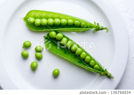 Green peas and pods arranged on a white plate 136788834