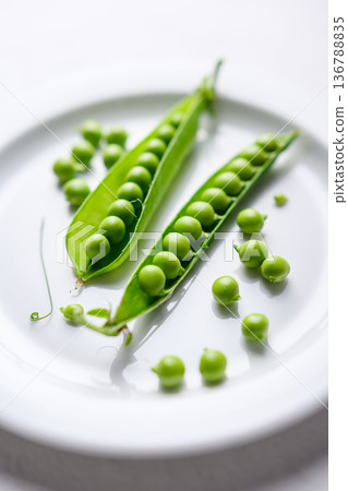 Green peas and pods on a white plate as natural food ingredients Green peas and pods on a white plate as natural food ingredients 136788835