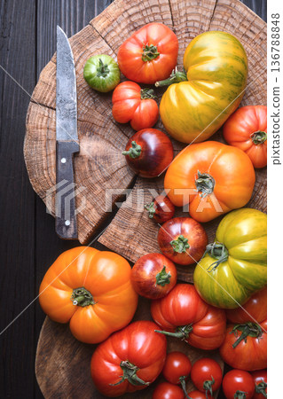 Mixed heirloom tomatoes with knife on wooden surface 136788848