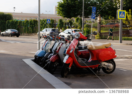 Colorful scooters parked neatly along a city street in the afternoon light Colorful scooters parked neatly along a city street in the afternoon light 136788988