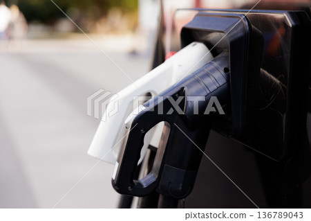 Modern electro car charger stands ready for eco-friendly journeys in a bustling urban setting Modern electro car charger stands ready for eco-friendly journeys in a bustling urban setting 136789043