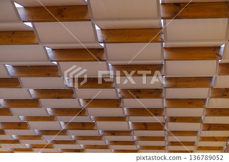 Artistic wooden ceiling design with an open pattern revealing light in a modern space Artistic wooden ceiling design with an open pattern revealing light in a modern space 136789052