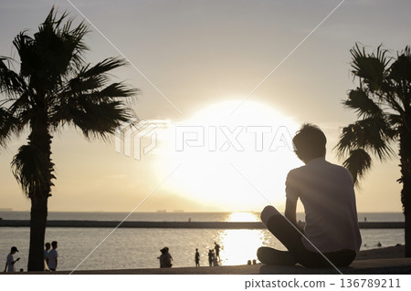 Silhouette of a man watching the sunset over the sea Silhouette of a man watching the sunset over the sea 136789211