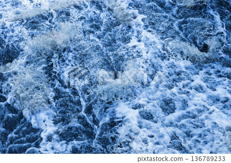 Blu stormy waves creating intricate white foam patterns 136789233
