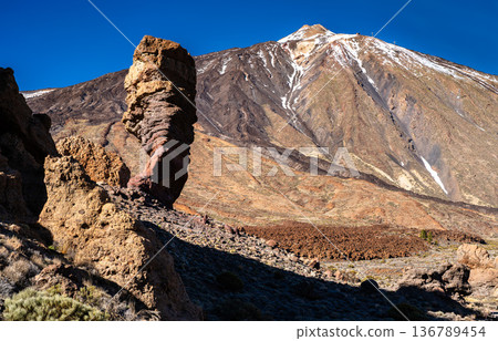 Scenic view of the famous Roque Cinchado rock formation and snow-capped Mount Teide volcano in Teide National Park, Tenerife, Canary Islands, Spain. The landscape features rugged volcanic rocks. 136789454