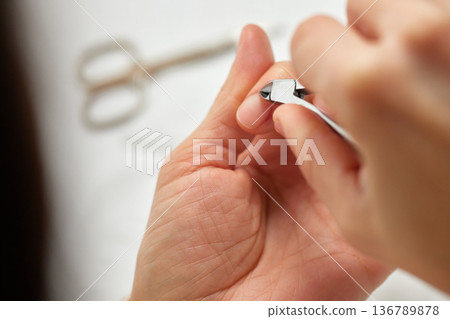 Woman trimming fingernail cuticles with nippers, focusing on hand grooming and hygiene 136789878