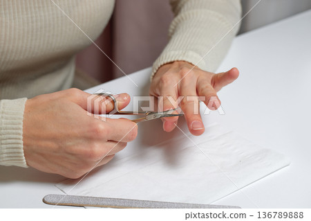 Woman meticulously caring for her hands and nails during a personal grooming session Woman meticulously caring for her hands and nails during a personal grooming session 136789888