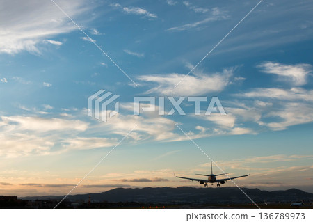 A passenger plane landing on the runway under a blue sky A passenger plane landing on the runway under a blue sky 136789973