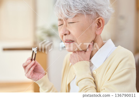 Senior Asian woman choking while eating Senior Asian woman choking while eating 136790011