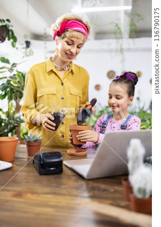A woman and a young girl enjoy a gardening activity, learning and having fun together A woman and a young girl enjoy a gardening activity, learning and having fun together 136790175