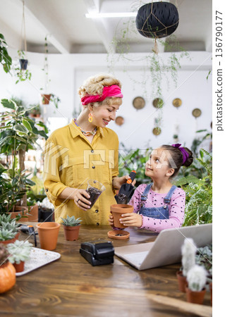 A woman and a young girl are potting plants, creating a heartwarming scene of family and gardening 136790177