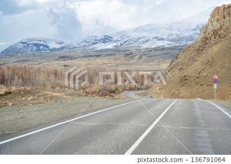Mountain road and valley of Chuysky Trakt Altai Russia. Scenic route through rugged terrain and expansive natural landscape Mountain road and valley of Chuysky Trakt Altai Russia. Scenic route through rugged terrain and expansive natural landscape 136791064