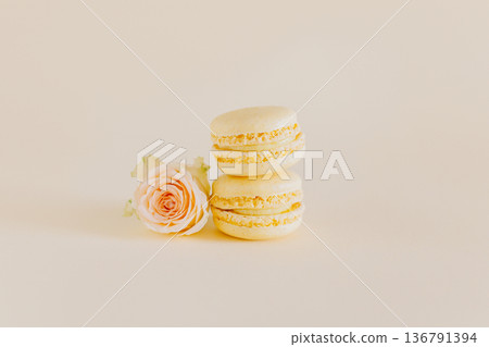 Tasty french macarons with tender rose flowers on a yellow pastel background. Tasty french macarons with tender rose flowers on a yellow pastel background. 136791394
