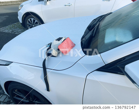 handbag on the hood of the car before getting behind the wheel. 136792147